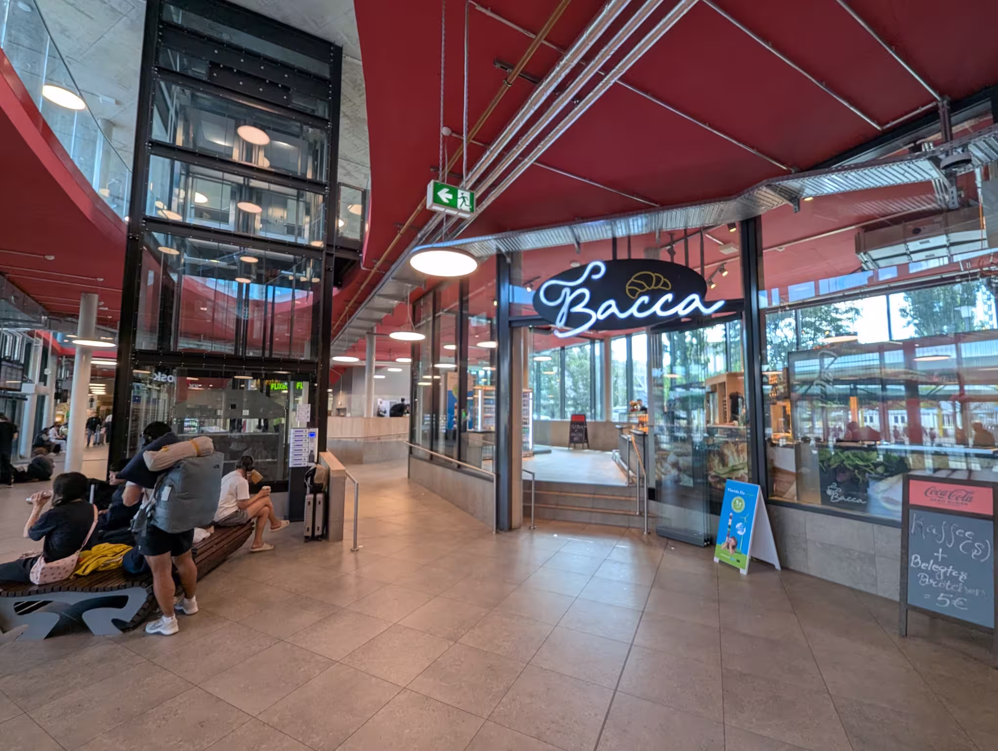 The center of the waiting hall with an elevator on the left and the bakery shop Bacca on the right